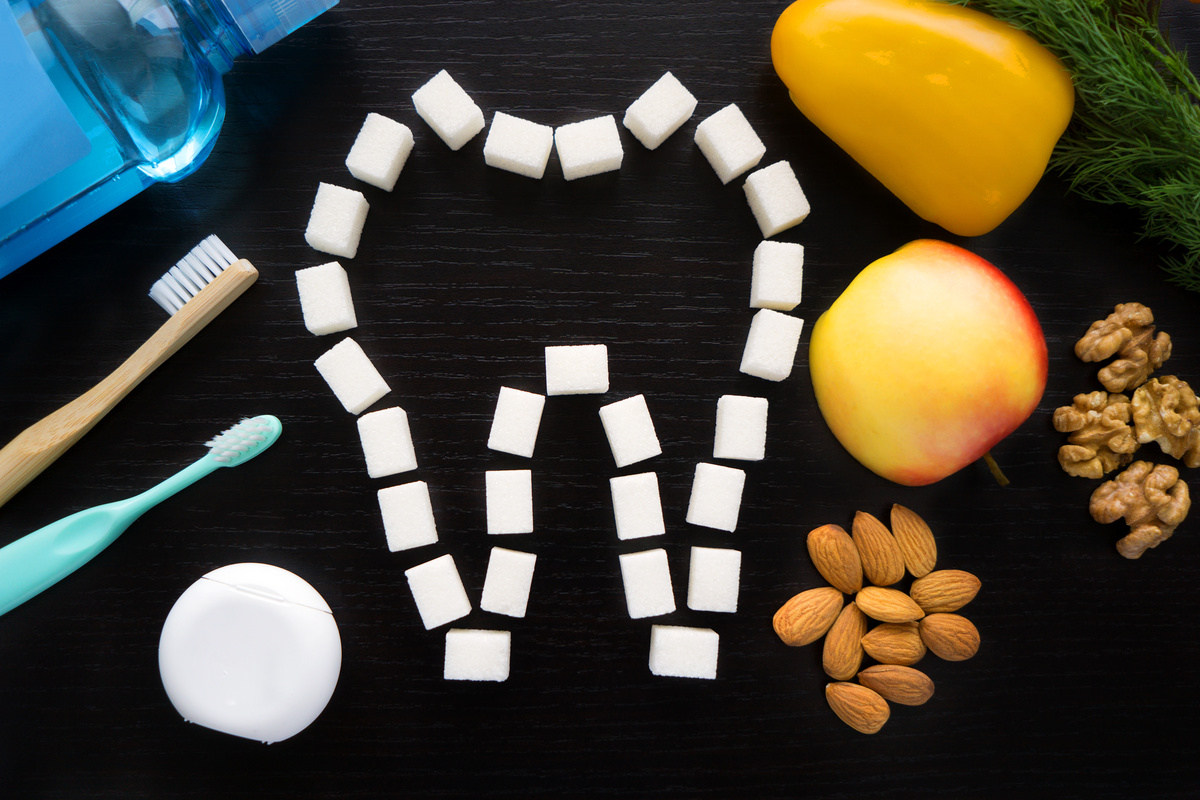 set for the care of the oral cavity - a bottle of mouthwash , tooth plastic and bamboo ecology brush and floss and eating the right foods to preserve your tooth on a black background