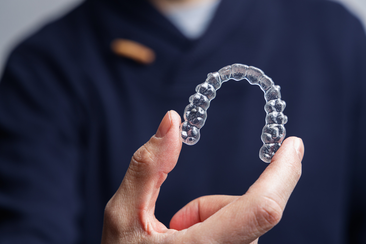 Man holding one transparent aligner. Invisalign orthodontics con