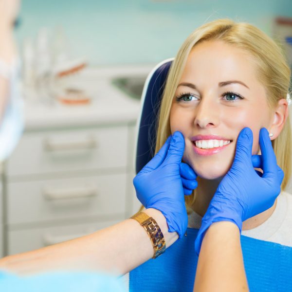 Female patient sitting in chair in dentist office for dental exam